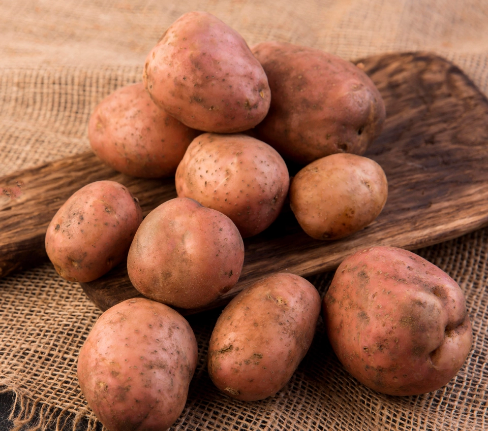 Algumas batatas em cima de uma tábua de mandeira