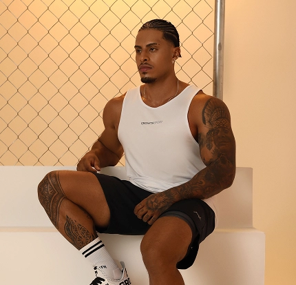 Atleta Growth Supplements sentado na escada de regata, shorts e meias Growth Supplements