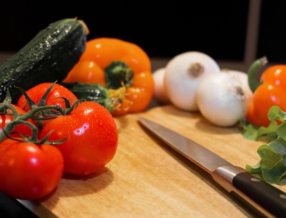Verduras ao lado como tomate, pimentão e alho e uma faca ao centro