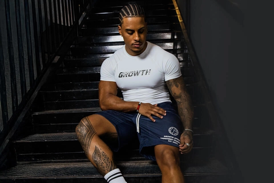 Modelo com camiseta e bermuda Growth Supplements sentado na escada
