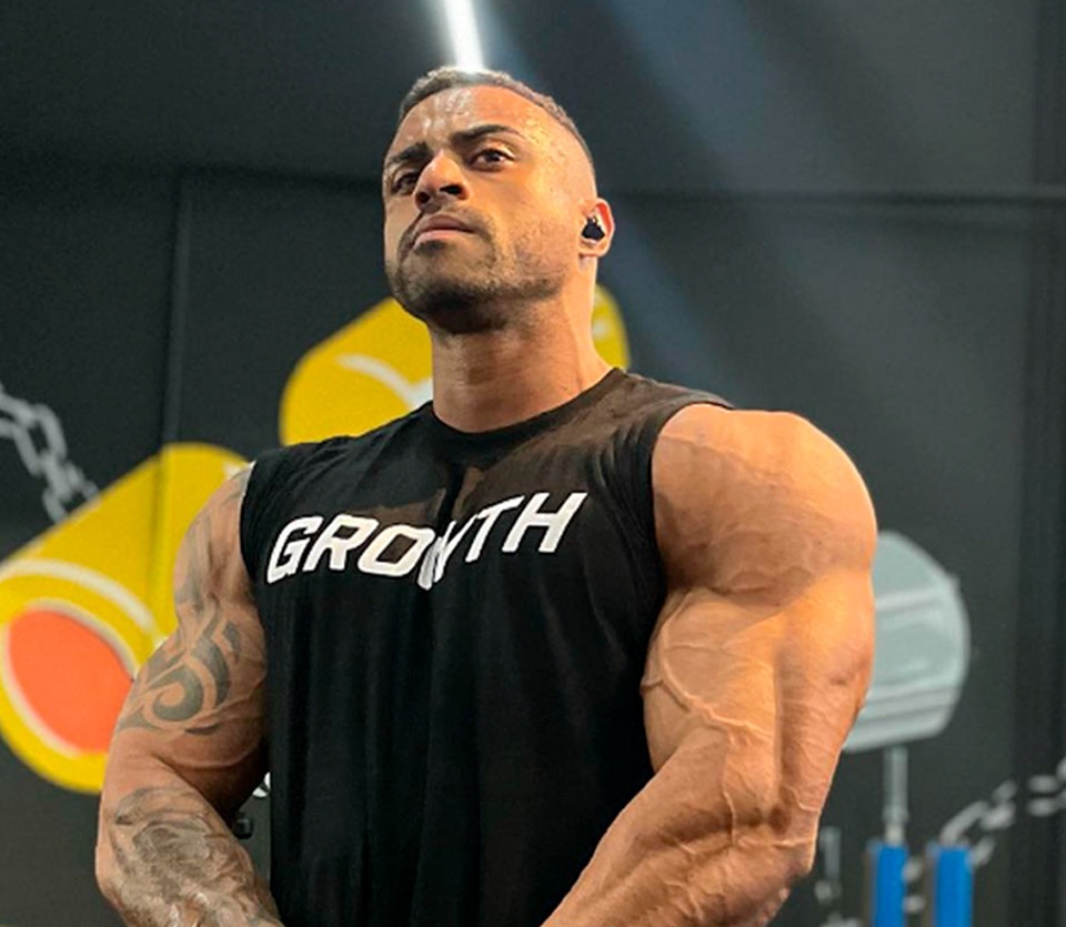 Rafael Oliveira Atleta Growth Supplements de regata e fone de ouvido mostrando os musculos superiores