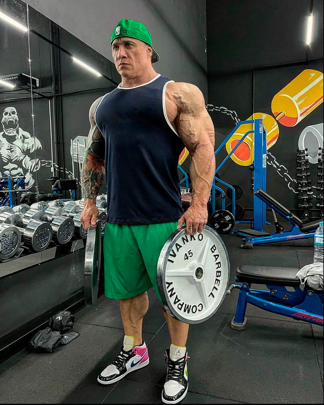 Atleta PRO Fabio Giga da Growth Supplements em pé segurando anilhas dentro de uma academia