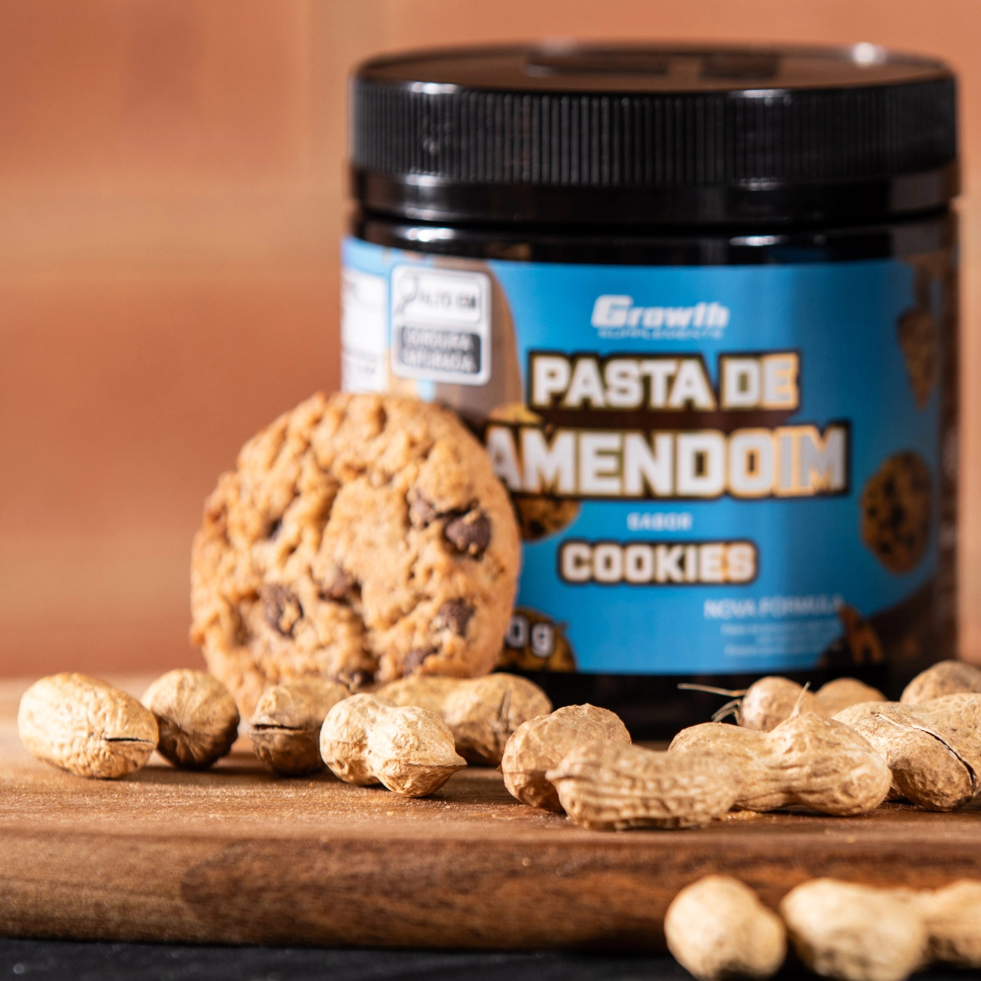 Pasta de amendoim sabor cookies com um cookie encostado e alguns amendoins ao lado