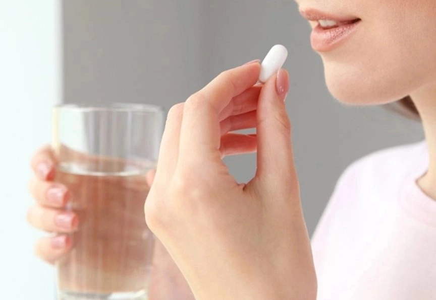 GROWTH SUPPLEMENTS - Imagem ilustrativa mulher levando comprimido à boca
