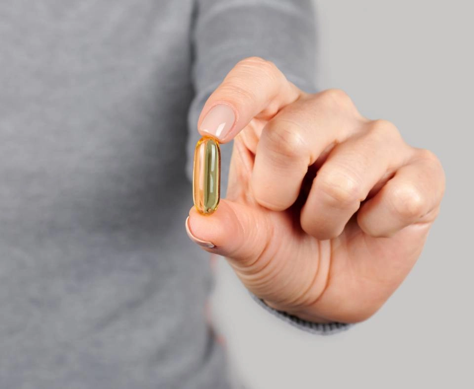 GROWTH SUPPLEMENTS - Imagem ilustrativa mão segurando um comprimido soft amarelo