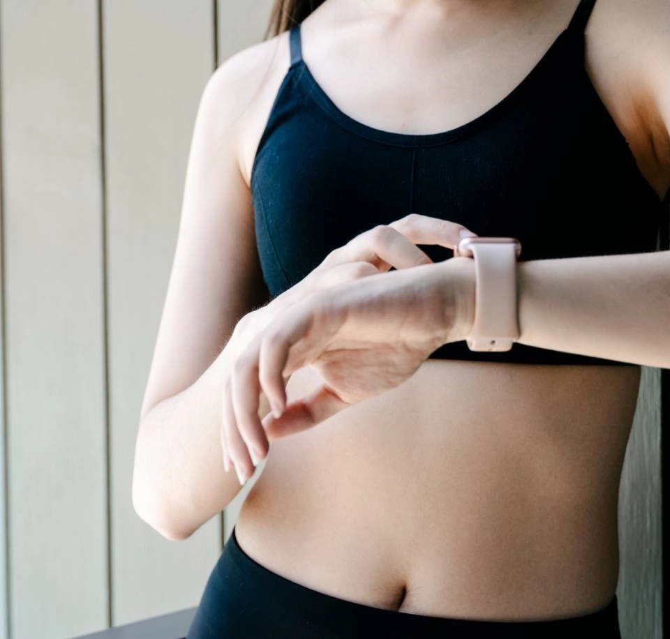 Mulher usando top e shorts preto mexendo no relogio inteligente