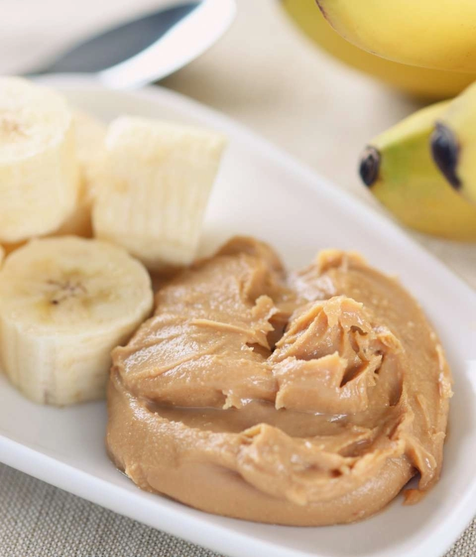 Pasta de amendoim sabor banana ao lado de fatias de uma banana