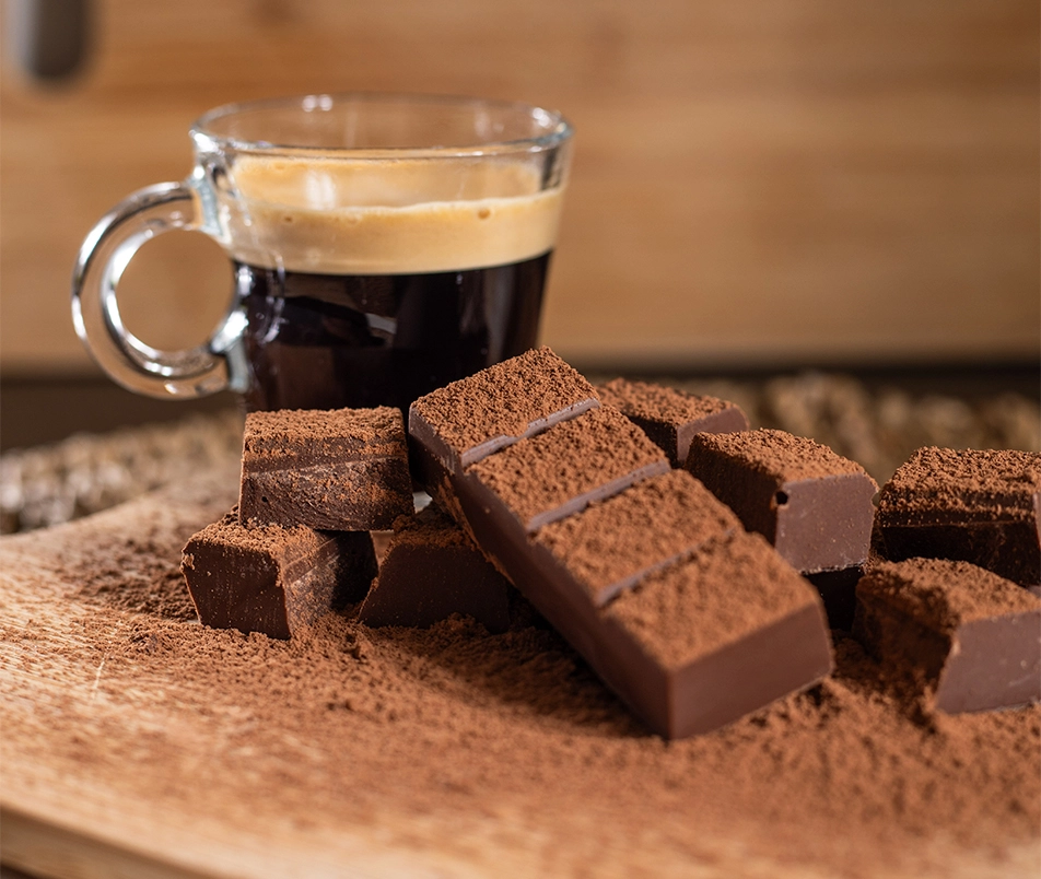 Chocolate Growth em cima de uma tábua de corte com uma xicara de café ao fundo