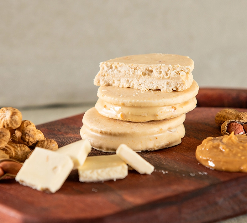 Alfajor com Whey Protein sabor chocolate branco empilhados em cima de uma tábua