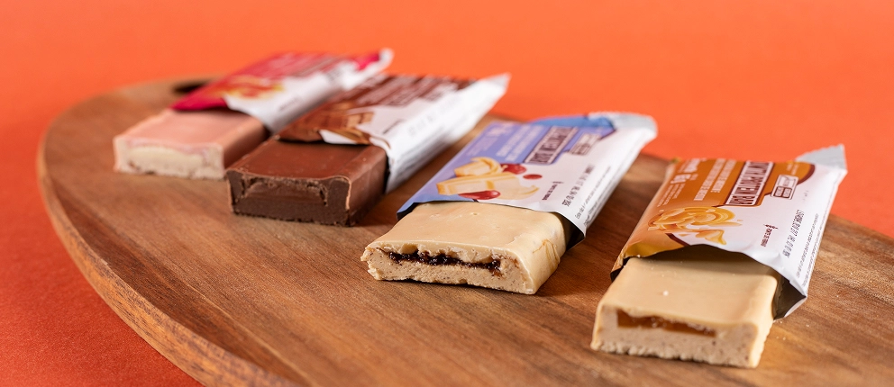 BARRA PROTEICA 65G Growth Supplements em cima de uma tábua de madeira